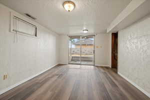 Empty room with hardwood / wood-style floors and a textured ceiling