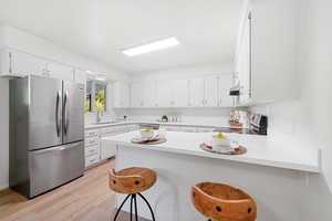 Kitchen with breakfast bar, new countertops,  white cabinetry, and stainless steel appliances