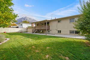 Rear view of house with a patio, a mountain view, and a yard