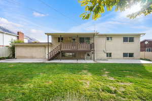 Back of house featuring a patio area, a lawn, and a garage