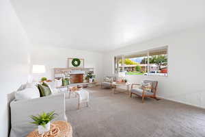 Carpeted living room featuring a stone fireplace