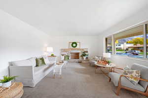 Carpeted living room with a fireplace and lots of natural light