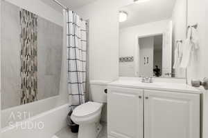 Full bathroom featuring vanity, shower / tub combo with curtain, and toilet