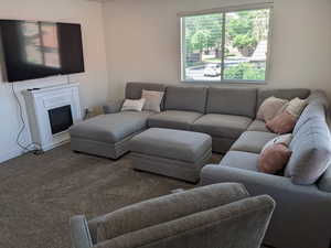 View of  living room, 65" television, hideaway ottoman, fireplace and ceiling fan