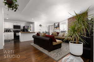 Living room with lofted ceiling, dark wood-type flooring, and a textured ceiling