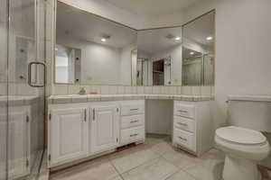 Master bathroom featuring a shower with door, vanity, toilet, and tile patterned floors