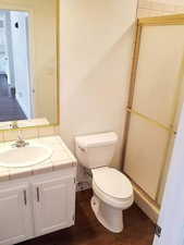 Main level second bathroom with vanity, toilet, hardwood / wood-style flooring, and an enclosed shower