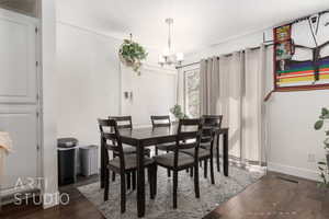 Dining area with dark wood-type flooring and a notable chandelier