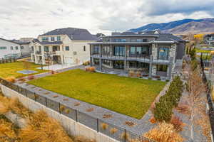 Rear view of house with a balcony, stone siding, a patio, board and batten siding, and a mountain view