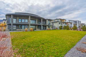 Rear view of property featuring a yard, stone siding, a balcony, and a residential view