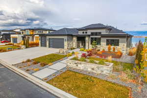 Prairie-style home featuring stone siding, driveway, an attached garage, and a shingled roof