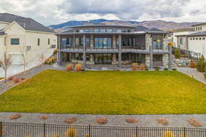 Back of house featuring stone siding, a mountain view, a balcony, and a patio