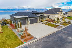 View of front facade with a mountain view, roof with shingles, an attached garage, driveway, and stone siding