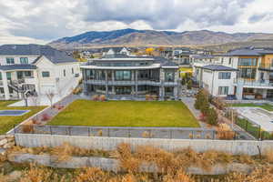 Rear view of property featuring a balcony, a mountain view, a residential view, and a fenced backyard