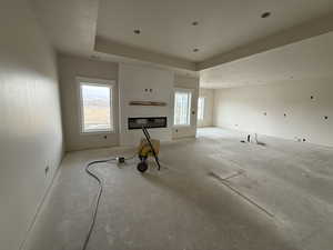 Unfurnished living room featuring a fireplace and a raised ceiling