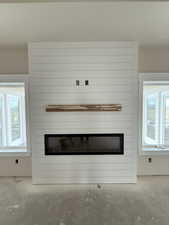 Room details featuring concrete flooring and a large fireplace