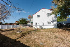 Back of house with central AC and a yard