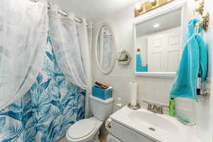 Bathroom with vanity, toilet, and tile walls