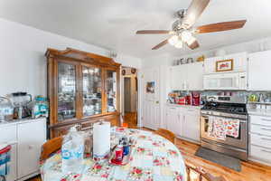 Kitchen featuring white cabinetry, light hardwood / wood-style flooring, stainless steel gas range, and backsplash