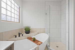 Bathroom featuring tile walls, vanity, and separate shower and tub