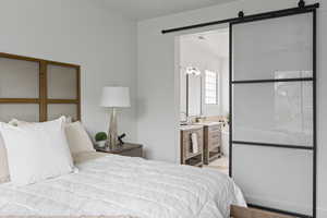 Bedroom featuring a barn door, sink, and connected bathroom