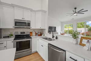 Kitchen featuring sink, appliances with stainless steel finishes, light hardwood / wood-style flooring, and white cabinetry