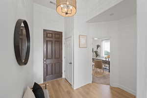 Entryway with light hardwood / wood-style flooring and an inviting chandelier