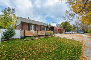 View of front of home featuring a wooden deck and a front lawn