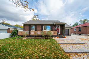 Ranch-style house featuring a front yard, a deck, and a garage