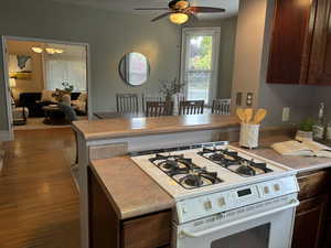 Kitchen with dark brown cabinets,  bar seating and white gas range