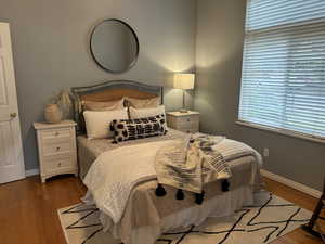 Bedroom with hardwood flooring, big window & attached full bathroom