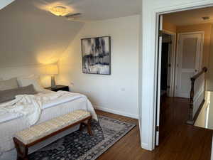 Upstairs bedroom featuring vaulted ceiling and dark hardwood / wood-style flooring