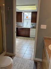 Bathroom with vanity, toilet, tile patterned floors, and walk in shower