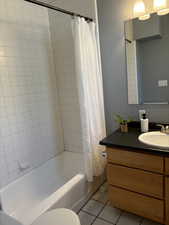 Full bathroom with vanity, shower / tub combo , tile  floors, and toilet