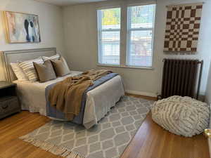 Bedroom featuring hardwood floors and radiator