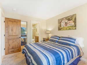 Bedroom featuring ensuite bathroom and carpet