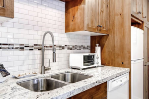 Kitchen with tasteful backsplash, sink, white appliances, and light stone countertops