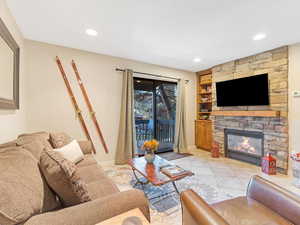 Living room with a stone fireplace, light tile patterned flooring, and built in features