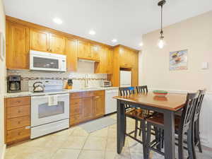 Kitchen featuring sink, pendant lighting, light tile patterned floors, light stone counters, and white appliances