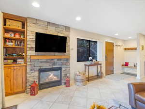 Living room with a stone fireplace and light tile patterned floors