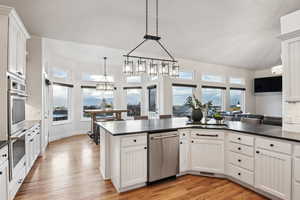 Kitchen with white cabinets, light hardwood / wood-style flooring, and pendant lighting