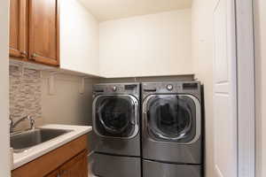 Laundry room with cabinets, washer and dryer, and sink