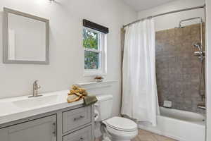 Full bathroom featuring vanity, shower / bath combo with shower curtain, toilet, and tile patterned floors