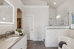 Bathroom with plus walk in shower, tile patterned flooring, ornamental molding, vaulted ceiling, and vanity