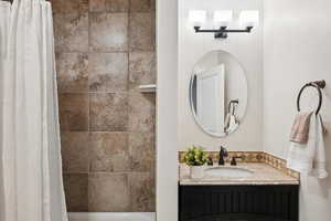 Bathroom featuring vanity and shower / bath combination with curtain