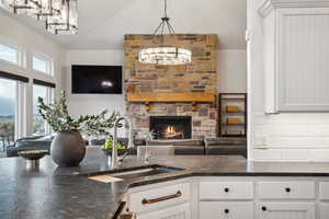 Kitchen with sink, white cabinets, a fireplace, and pendant lighting