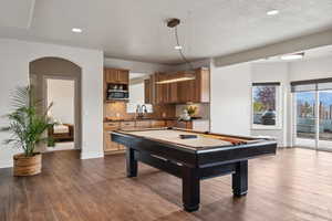 Playroom featuring pool table, a textured ceiling, sink, and dark wood-type flooring