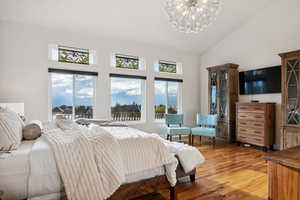 Bedroom with a notable chandelier, hardwood / wood-style flooring, and high vaulted ceiling