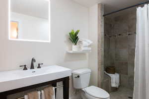 Bathroom featuring vanity, curtained shower, and toilet