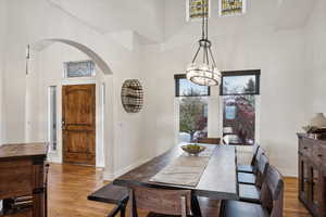 Dining room with a high ceiling, a notable chandelier, and light wood-type flooring